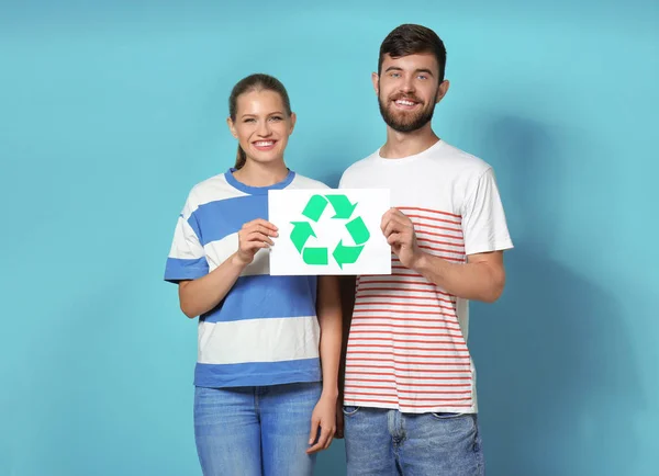 背景の色のシンボルのリサイクル紙を抱いた若い夫婦 — ストック写真