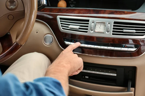 Jongeman inschakelen airconditioningsysteem in auto — Stockfoto