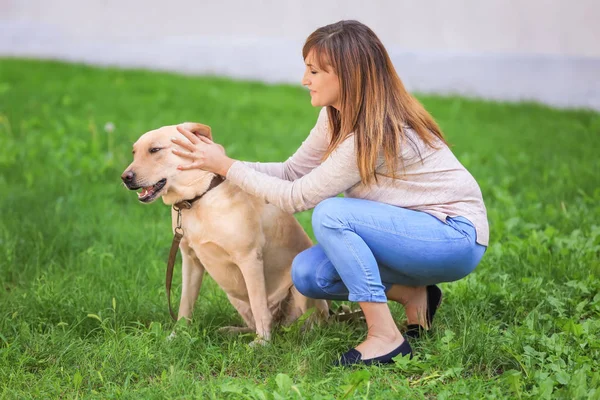 Rijpe vrouw met haar hond in park — Stockfoto