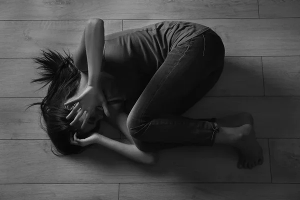 Poobijany, młoda kobieta, leżąc na podłodze — Zdjęcie stockowe