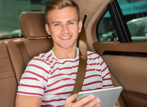 Arabanın arka koltukta tablete ile yakışıklı genç