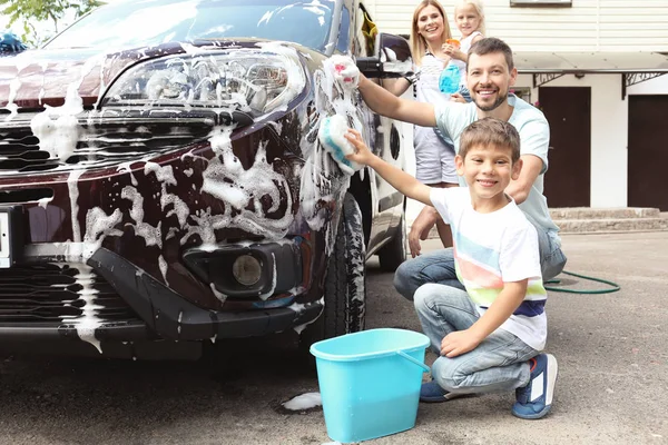 Lycklig familj tvätt bil utomhus — Stockfoto