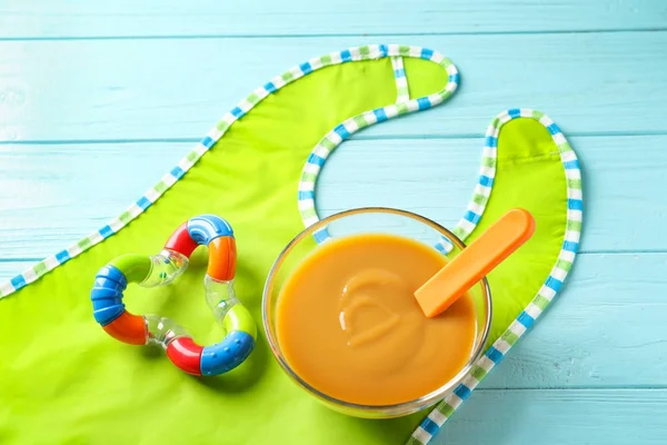 Bol en verre avec nourriture pour bébé et bavette — Photo