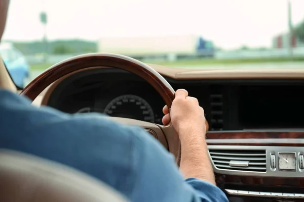 Young man holding hand on steering wheel of car — Stock Photo, Image