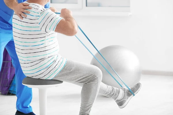 Fisioterapeuta trabajando con un paciente mayor en una clínica moderna — Foto de Stock