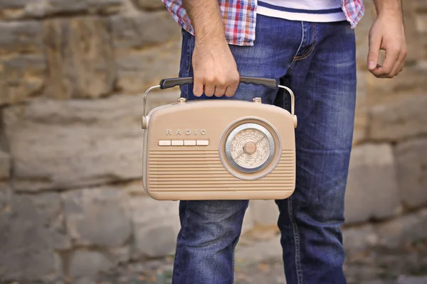 Young man with retro radio on brick wall background