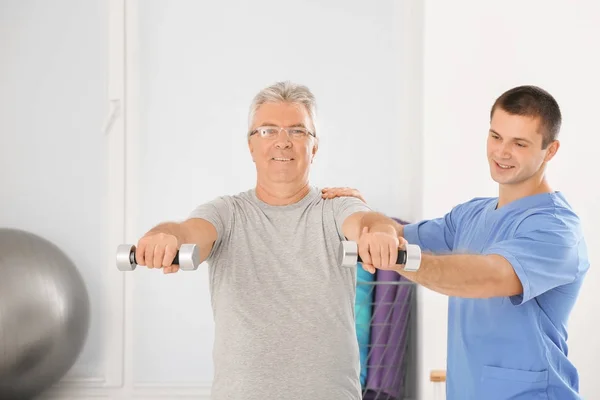 Fysiotherapeut werken met senior patiënt in moderne kliniek — Stockfoto