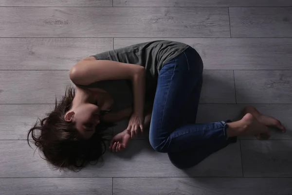 Mujer joven maltratada acostada en el suelo —  Fotos de Stock