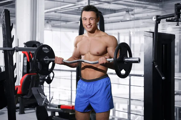 Sportlicher junger Mann trainiert mit Langhantel im Fitnessstudio — Stockfoto