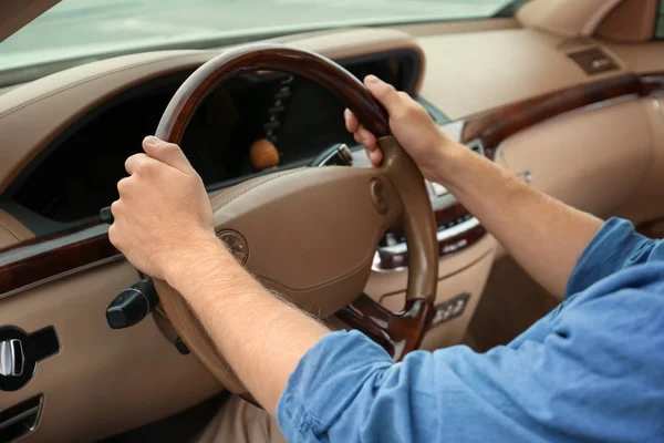 Giovane uomo che si tiene per mano sul volante della macchina — Foto Stock