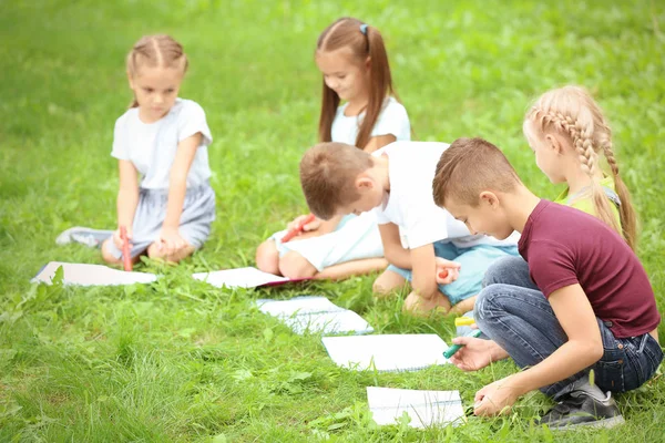 Lindos niños pequeños dibujando imágenes sobre hierba verde —  Fotos de Stock