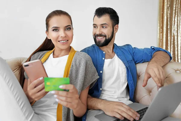 Νεαρό ζευγάρι με laptop και smartphone στο σπίτι. Έννοια αγορών στο διαδίκτυο — Φωτογραφία Αρχείου