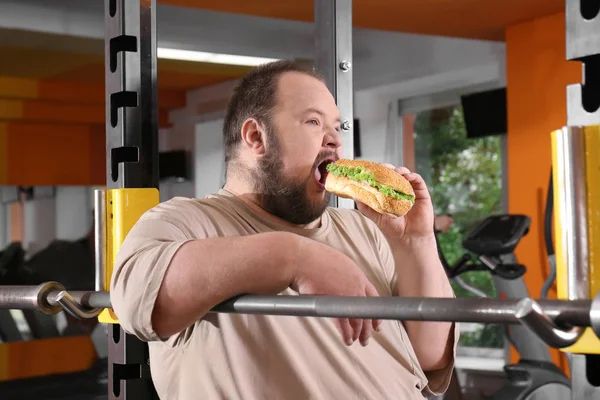 Overgewicht man eten sandwich in sportschool — Stockfoto