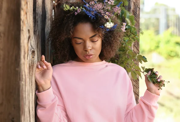 Vackra unga afroamerikanska kvinna med blommor utomhus — Stockfoto