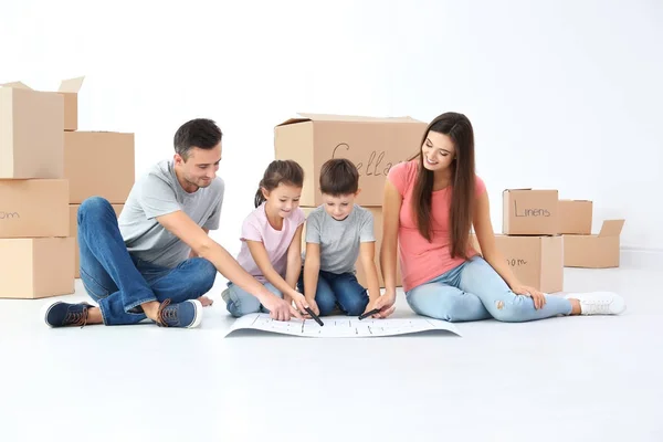 Familia examinando el plan de casa en el piso — Foto de Stock