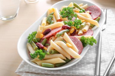 Sosis ve açık renkli seramik kase sebze ile makarna