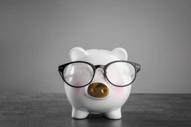 Gri arka plan karşı masada gözlüklü şirin kumbara