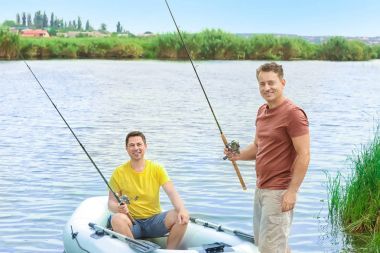 İki adam Nehri üzerinde şişme tekneden Balık tutma