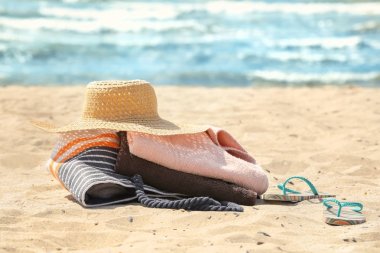 Plaj havlusu, şapka ve çanta kum üzerinde