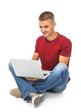 Yakışıklı genç bir adam oturuyor ve kullanma laptop beyaz arka plan