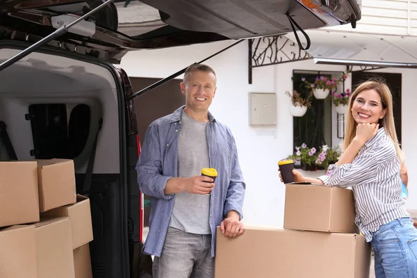 Pareja feliz con café y cajas móviles cerca del coche —  Fotos de Stock