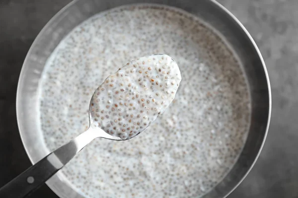 Tigela e colher com pudim de semente de chia em fundo cinza, close-up — Fotografia de Stock