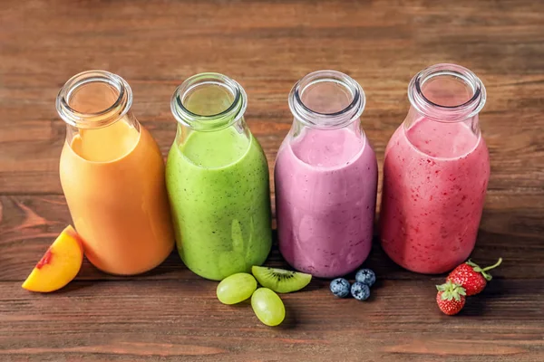 Bottles with yummy smoothie on wooden background — Stock Photo, Image