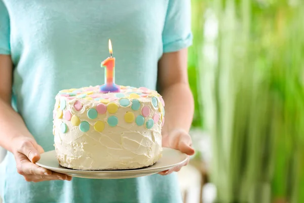 Жінка тримає торт зі свічкою на перший день народження, крупним планом — стокове фото