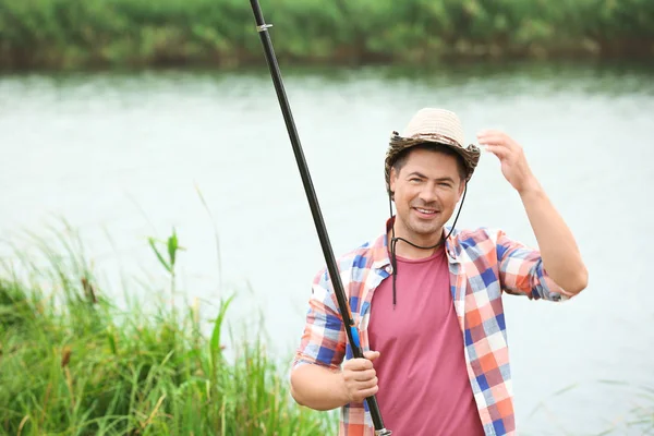 Joven pescando en la orilla del río — Foto de Stock