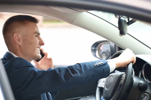 Красивый молодой бизнесмен разговаривает по мобильному телефону в современной машине — стоковое фото