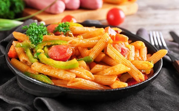 Pasta with sausage in portioned frying pan on fabric — Stock Photo, Image