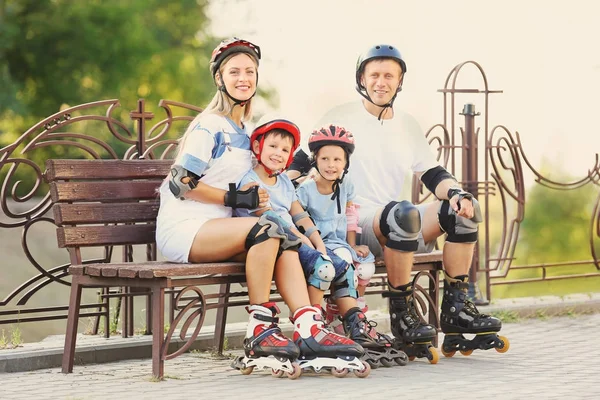 Familj på rullskridskor sitter i parken — Stockfoto