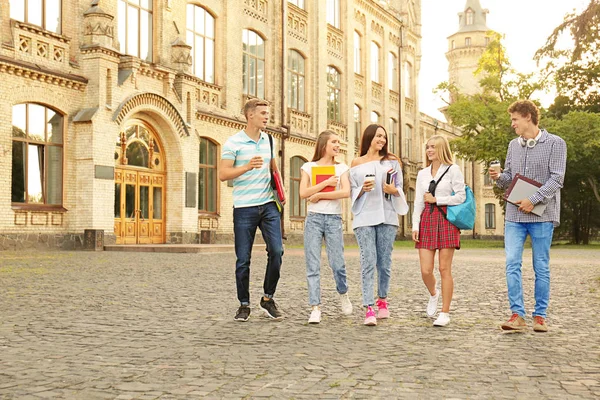 Skupina mladých studentů pěší poblíž univerzitní budovy — Stock fotografie