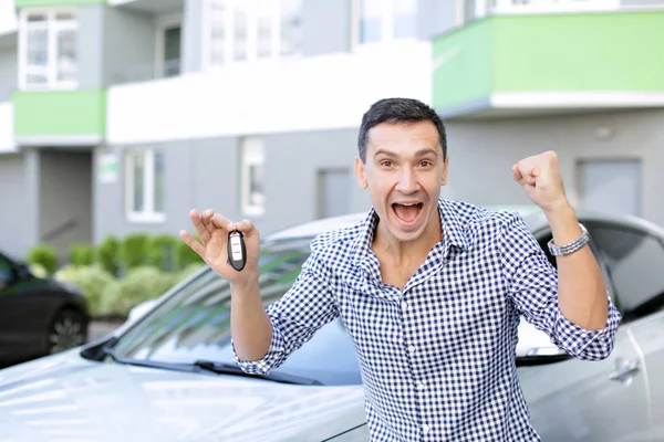 Uomo felice con chiave in piedi vicino auto nuova — Foto Stock