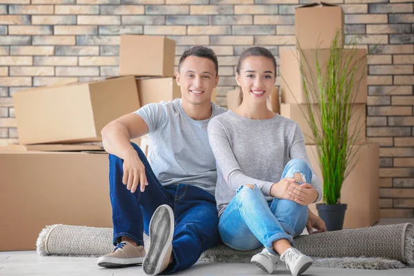 Gelukkige jonge paar zittend op de vloer in hun nieuwe appartement in de buurt van Verhuisdozen — Stockfoto