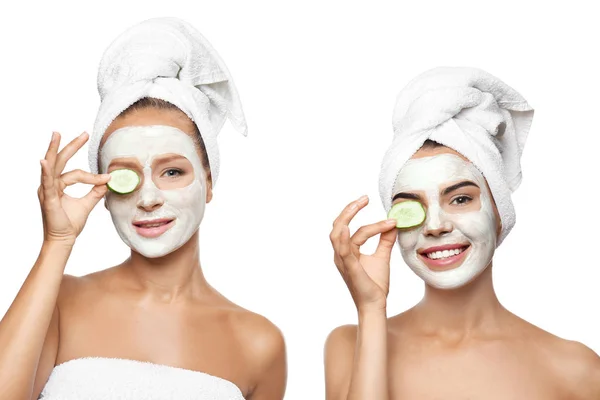 Young women with facial masks and cucumber slices on white background — Stock Photo, Image