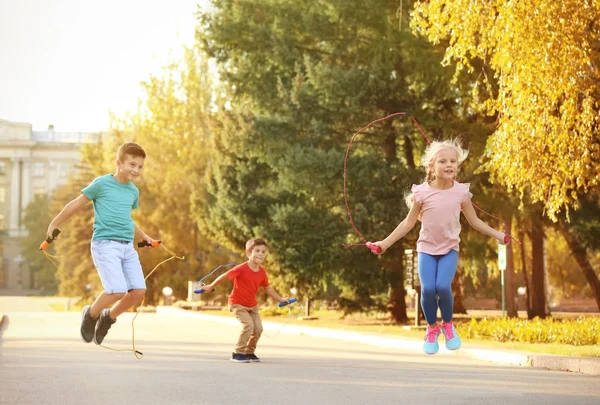 Adorables niños saltando la cuerda al aire libre — Foto de Stock