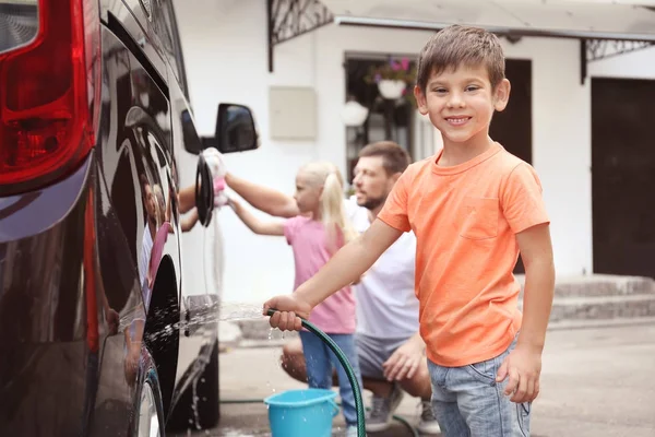 Очаровательный маленький мальчик моет машину на открытом воздухе — стоковое фото
