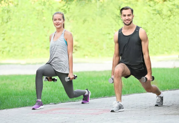 Jonge man en vrouw doen oefeningen in park — Stockfoto