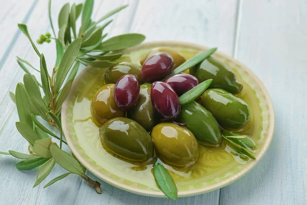Piatto con olive in scatola su fondo di legno bianco — Foto Stock