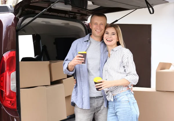 Gelukkige paar met koffie en Verhuisdozen in de buurt van auto — Stockfoto