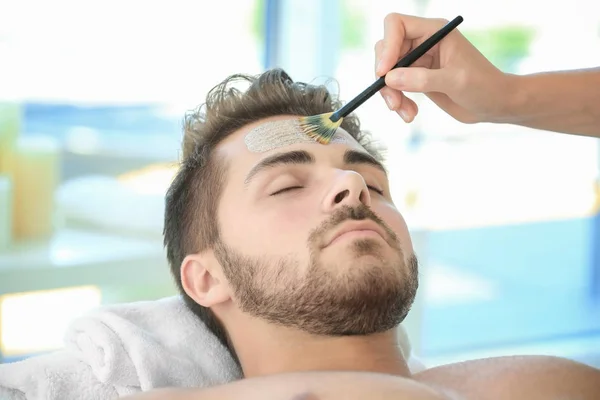 Beautician applying scrub onto face