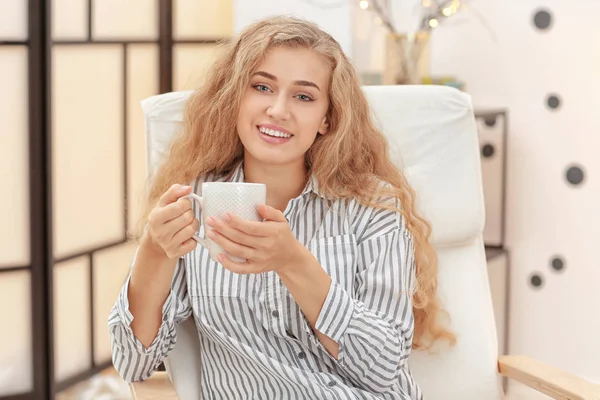 Joven hermosa mujer sentada en sillón en casa — Foto de Stock