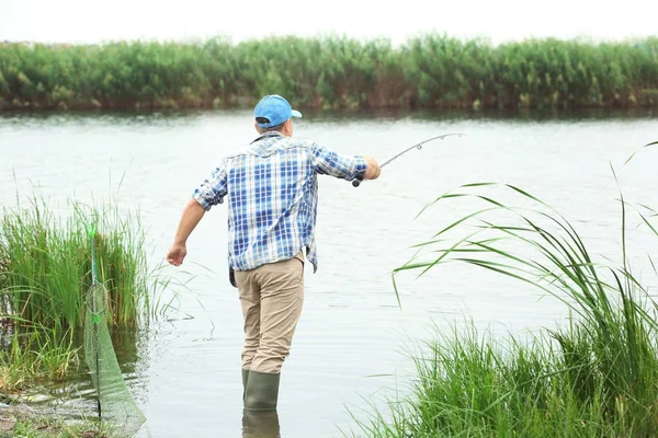 Hombre pescando en la orilla del río — Foto de Stock