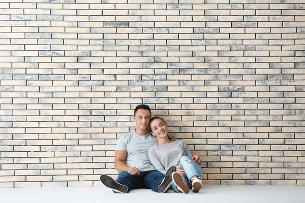 Mutlu genç çift tuğla duvar yeni apartmanda yakın katta oturuyor. Hareketli ev kavramı — Stok fotoğraf