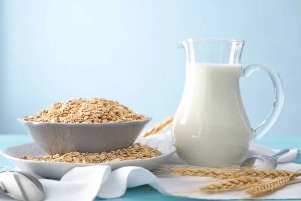 Dishware with oatmeal flakes and pitcher of milk — Stock Photo, Image