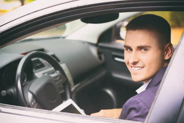Knappe jonge zakenman met behulp van tablet pc in moderne auto — Stockfoto