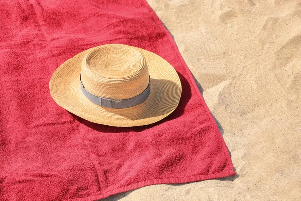 Toalha de praia vermelha e chapéu na areia — Fotografia de Stock