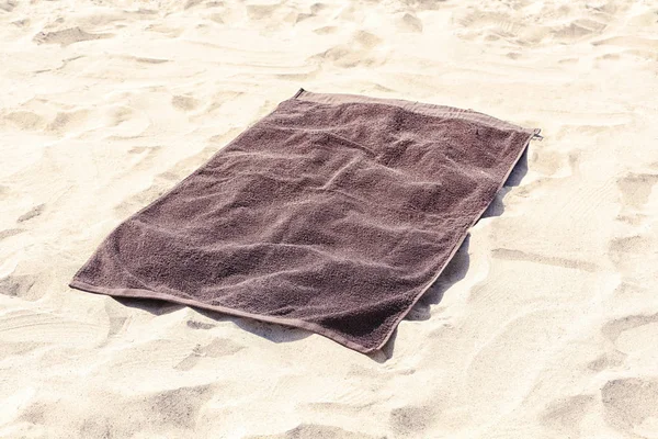 Toalla de playa marrón sobre arena Imagen de archivo