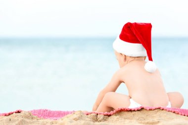 Noel Baba şapkalı plajda şirin çocuk